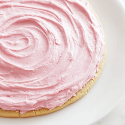 A close-up shows thick Giant Chilled Crumbl Sugar Cookies with soft centers and swirled pink frosting ready to serve.